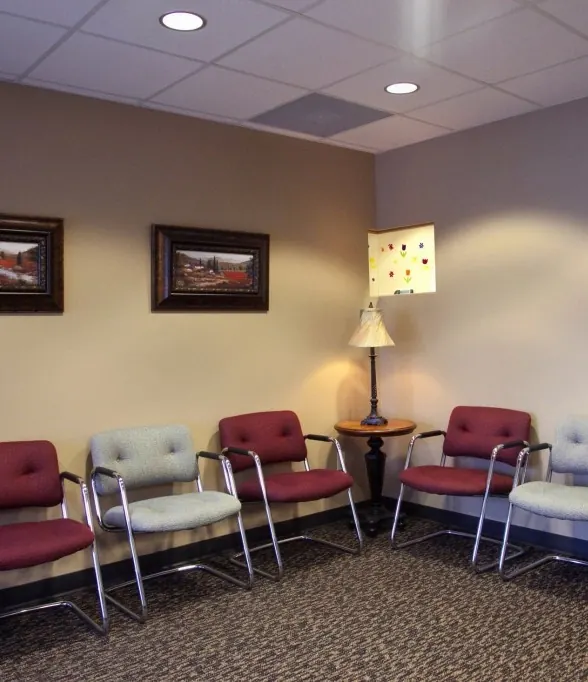 Waiting room chairs in red and grey beneath framed paintings.