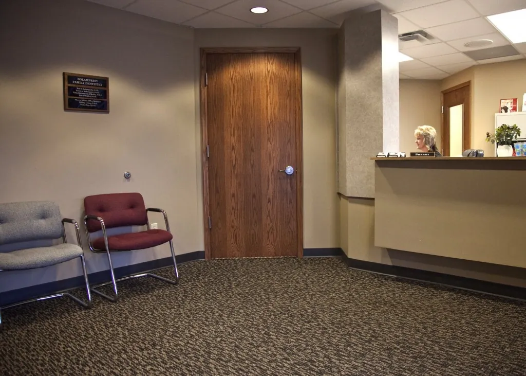 The waiting area and reception desk, with a wooden door to the treatment rooms.
