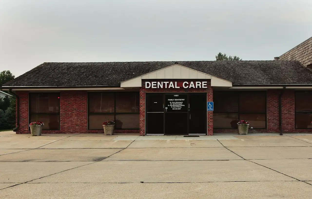 The West Center Road office of Bolamperti & O&rsquo;Malley Family Dentistry, a single-storey red brick building with a Dental Care sign over the entrance.