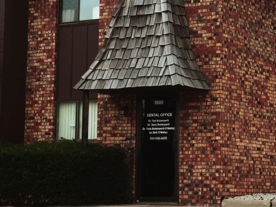 The entrance to the 50th Street office, a brick building with a wood-shingle awning over the door.